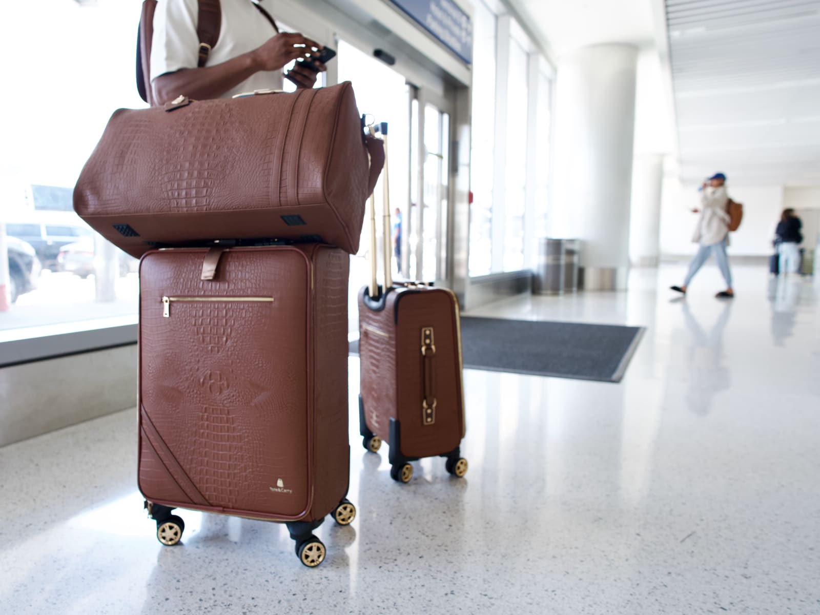 A two-piece brown crocodile-embossed luggage set in an airport terminal
