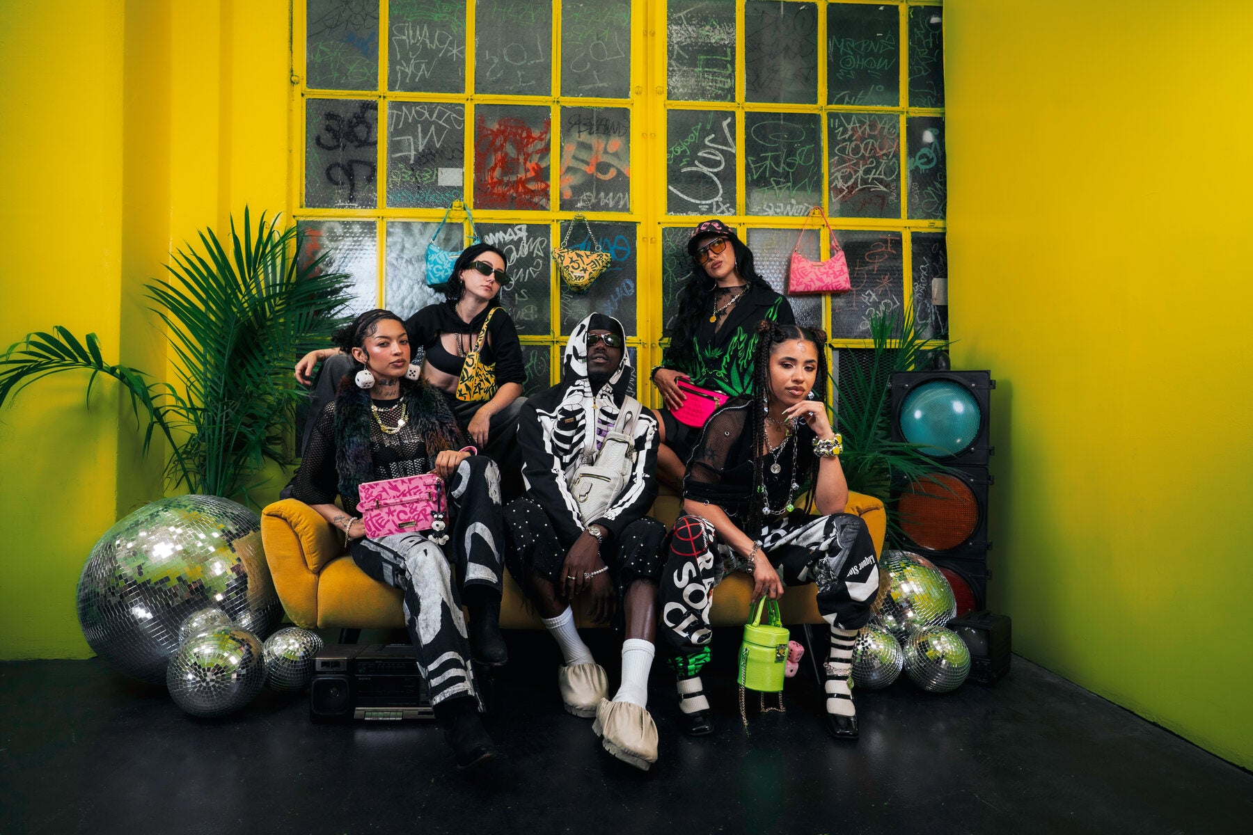Five creators on a yellow couch with Tote&Carry bags in a graffiti studio